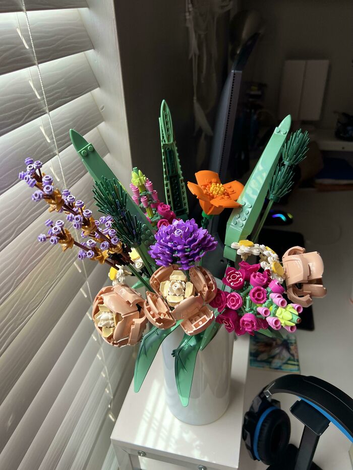 Colorful LEGO flower bouquet in a white vase displayed by a window, showcasing incredible LEGO builds as works of art.
