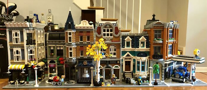 Intricate LEGO builds forming a detailed street scene with various buildings and miniature figures on display.