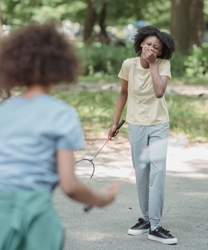 Two people playing badminton outdoors, enjoying fun activities to avoid boredom at home.