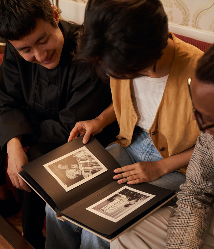 Three friends enjoying a photo album at home, finding fun things to do together.