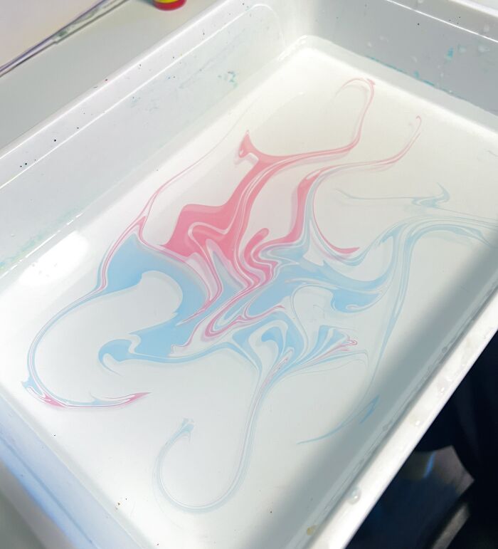 Fluid marbling art with pink and blue swirls in water, reminiscent of sernakkab technique. Fluid marbling art with pink and blue swirls in water, reminiscent of sernakkab technique.