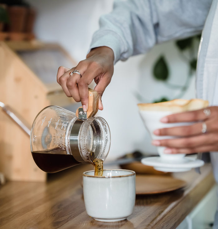 Hand pouring coffee at home, a fun activity to avoid boredom.