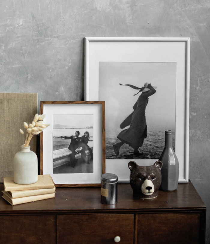 Stylish home decor setup with framed photos, books, and ceramic vases on a wooden table to avoid boredom.