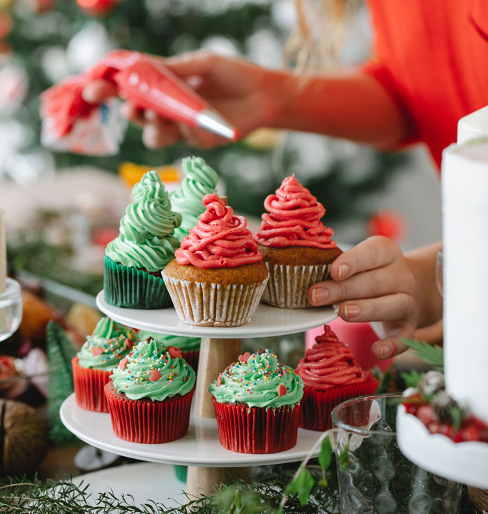 Decorating cupcakes at home with festive green and red frosting to avoid boredom.