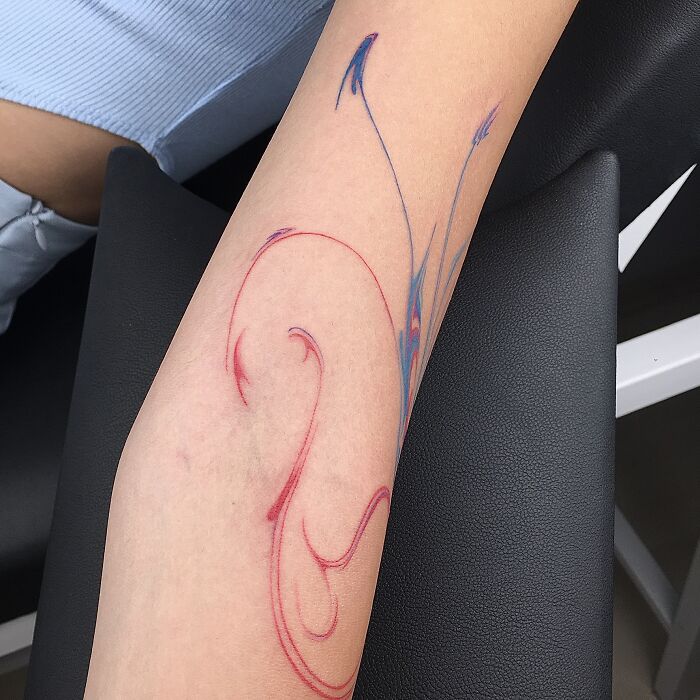 Arm with flowing tattoo design inspired by traditional Sernakkab marbling, featuring red and blue swirls. Arm with flowing tattoo design inspired by traditional Sernakkab marbling, featuring red and blue swirls.