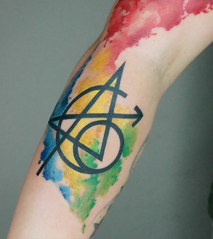 Colorful Marvel tattoo on arm with abstract geometric design.