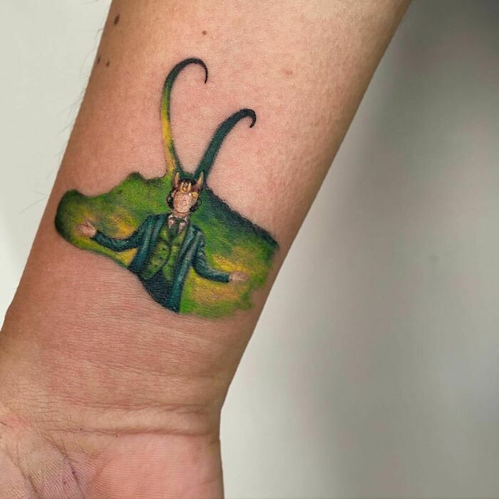 Loki-themed Marvel tattoo with vibrant green and yellow hues on a forearm.