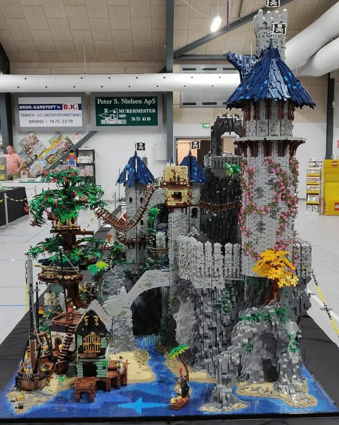 Intricate LEGO builds featuring a detailed castle with towers, bridges, and surrounding landscape in an indoor exhibit.