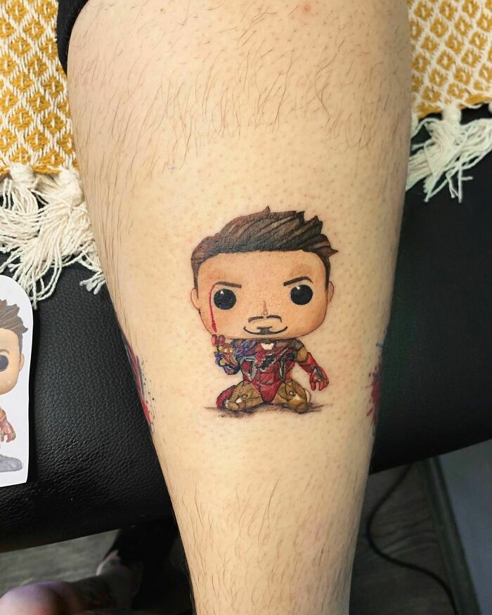 Chibi superhero Tony tattoo on leg, showcasing detailed Marvel design.