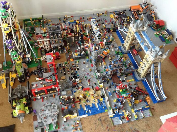 Large LEGO scene featuring detailed builds including a castle bridge, Ferris wheel, ships, and numerous minifigures.