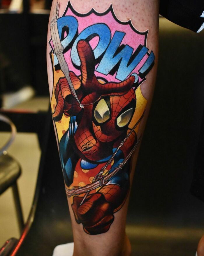 Marvel tattoo of Spider-Man on a leg with vibrant colors and comic-style "POW!" text.