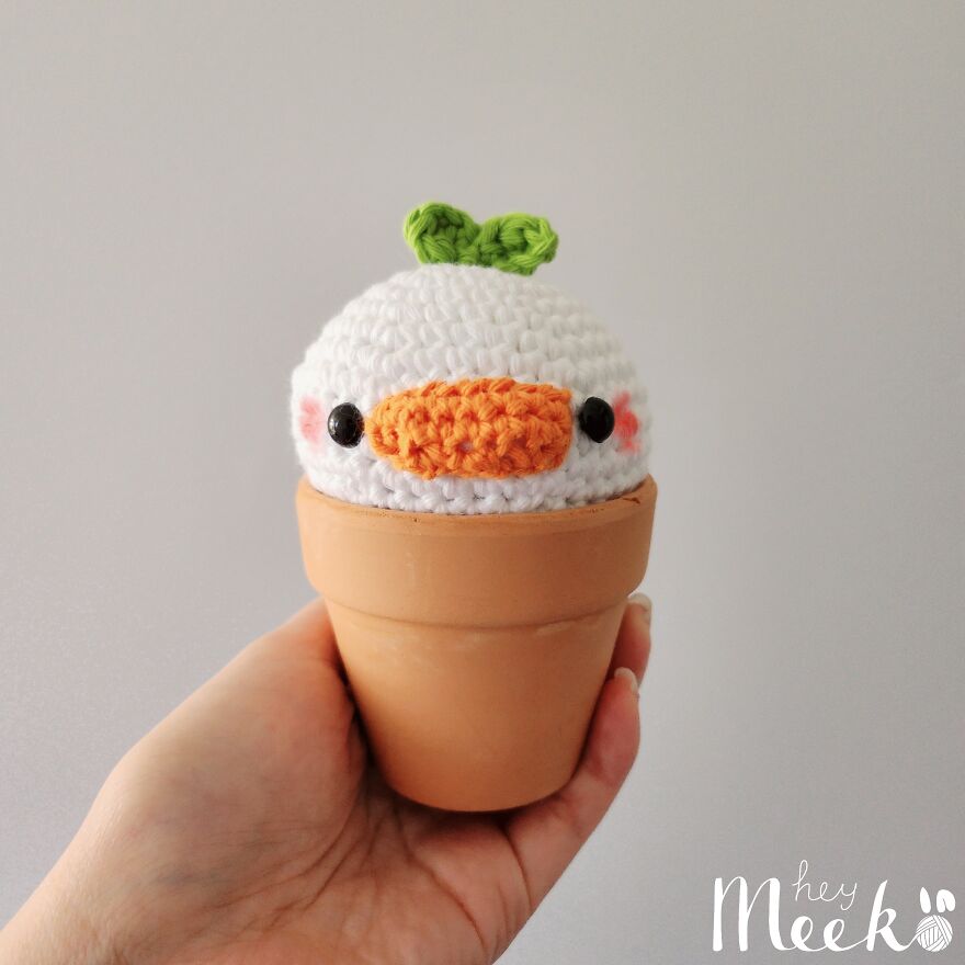 Hand holding a crocheted duck in a pot, showcasing cute crochet creations for a side hustle.