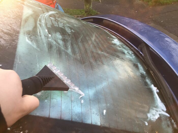Person Scraping Ice From The Window After Night 