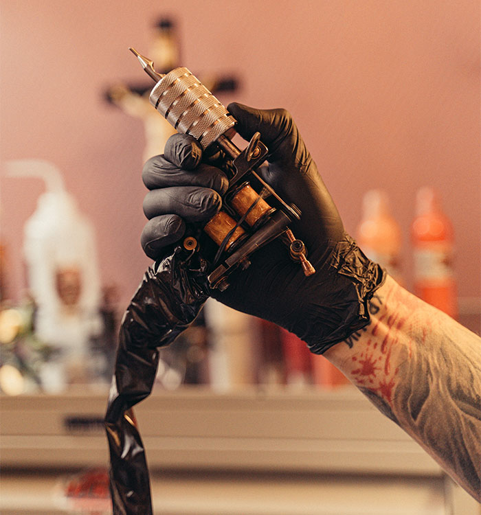 Tattoo artist holding tattoo machine, highlighting "medical tattoo" procedure for boy as recommended by a doctor.