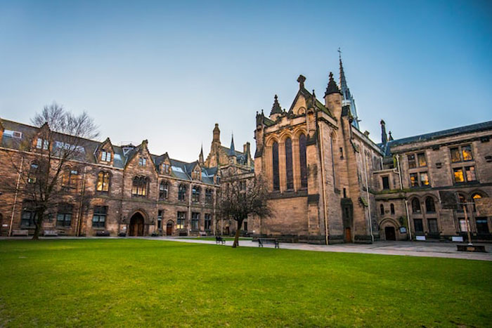 Historic stone university buildings surrounding a green lawn, illustrating people sharing dumbest and most expensive mistakes.