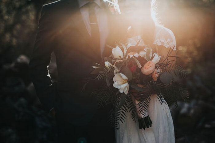 Couple in wedding attire holding a bouquet, illustrating a costly and dumb mistake seen by others in life events.