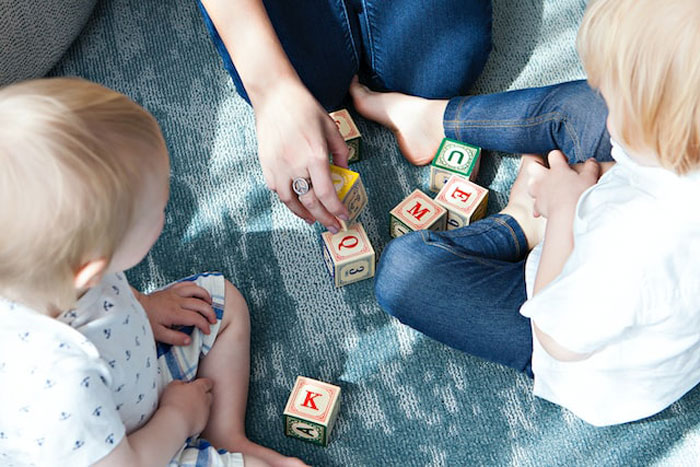 Two children playing with alphabet blocks on a carpet, illustrating the concept of expensive mistakes and learning moments.