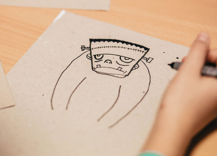 Person drawing a Frankenstein-inspired character sketch with a marker, illustrating one of many creative drawing prompts ideas.