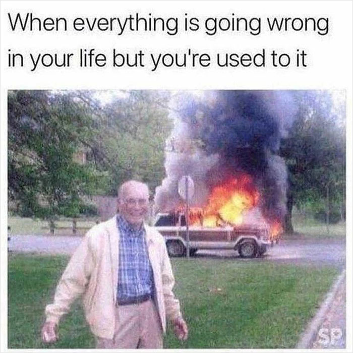 Man smiling in front of a burning car, representing feeling overwhelmed by life. Meme text reads: "When everything is going wrong."