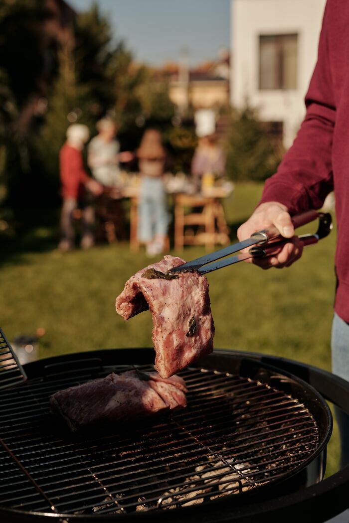 Person Flipping A Piece Of Meat On A Grill 