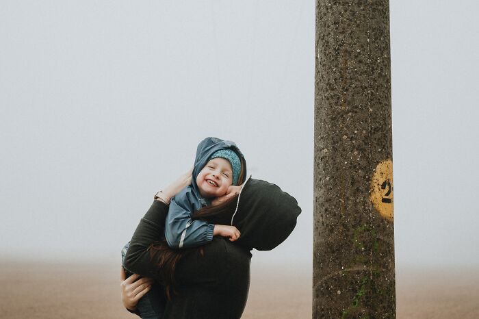 Woman Holding Her Baby And Kissing Him On The Cheek 