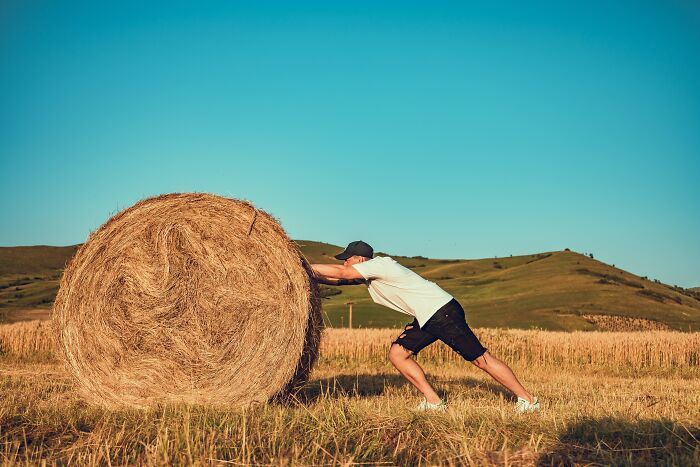 Man Pushing A Hail Bale Outside