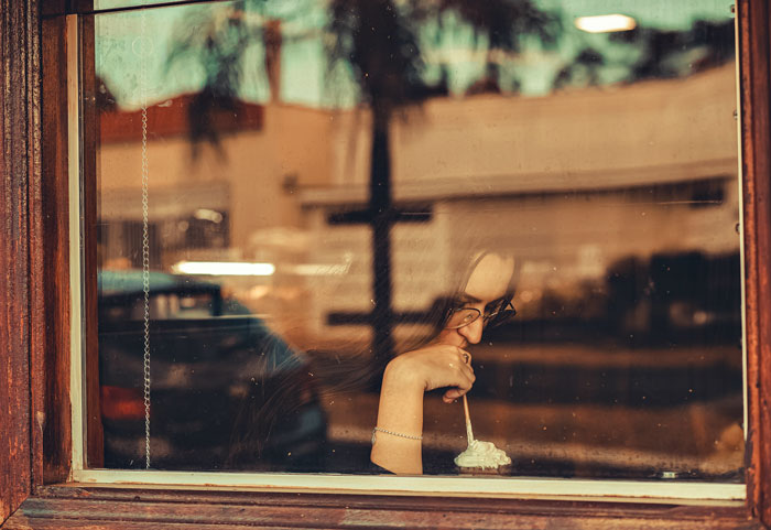 Woman drinking coffee near window