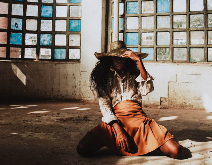 Woman sitting on the ground and holding hat