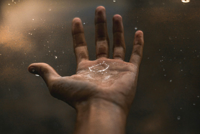 Person holding hand with water drops