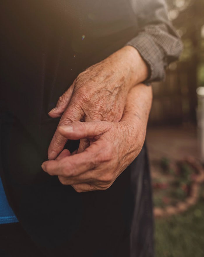 Close-up of elderly hands clasped together, evoking eerie feelings related to children's imaginary friends stories.