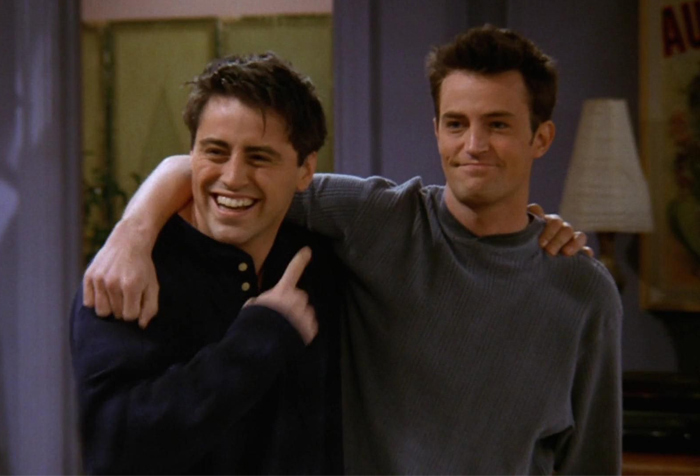 Two friends smiling with one arm around the other, illustrating signs of a fake friend and toxic relationship.