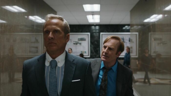 Two men in suits in a tense conversation, illustrating signs of a fake friend and toxic relationship.