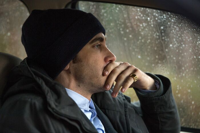 Man in a beanie sitting in a car looking thoughtful, reflecting on signs of a fake friend and toxic relationship.