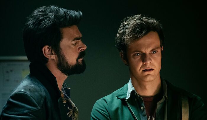 Two men in a tense conversation illustrating signs of a fake friend and a toxic relationship in a dimly lit room.