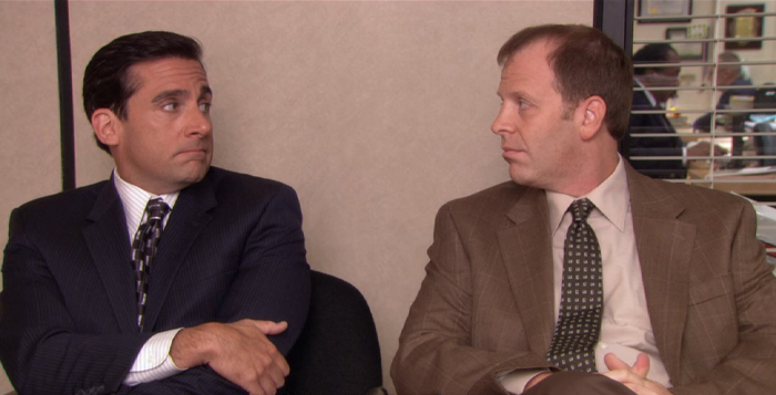 Two men in business suits sitting side by side, showing signs of discomfort hinting at a toxic relationship.