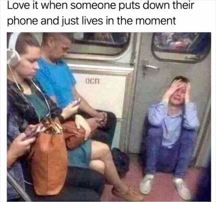 People on a subway engrossed in phones, while a man sits overwhelmed, capturing life's chaos and tiredness.