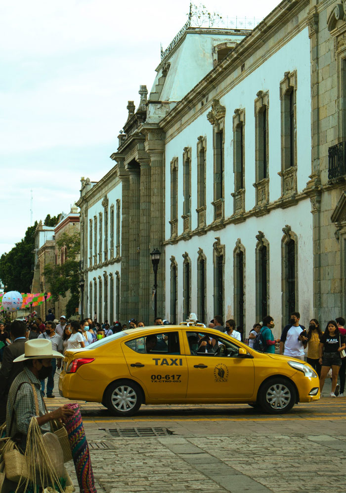 yellow taxi car parked on road near concrete building