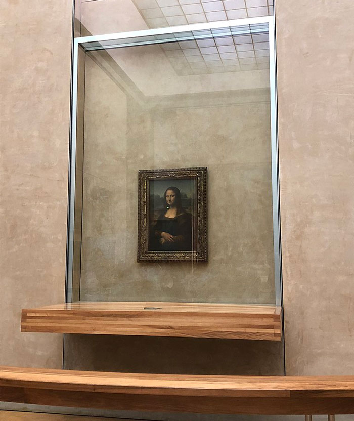 Mona Lisa painting displayed in Louvre behind protective glass showcasing curious facts in art classes.