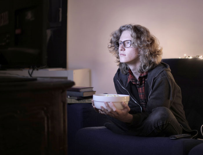 Woman watching tv with a bowl 