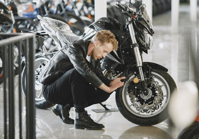 A man in black leather jacket sitting beside the motorbike