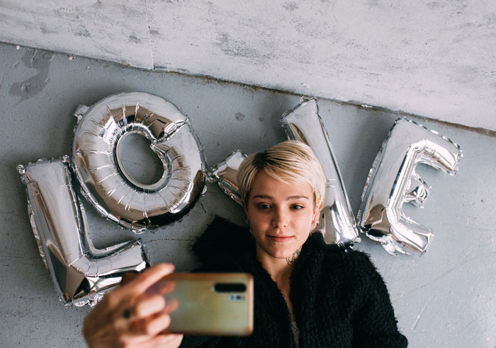 A woman taking selfie in front of balloons 