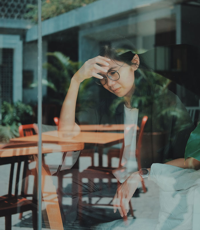 Woman wearing glasses, sitting behind the table 