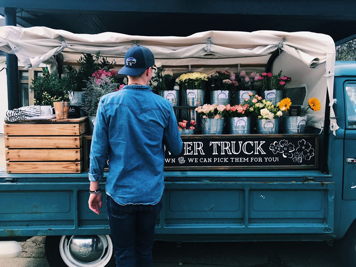 Man near truck filed with flowers 