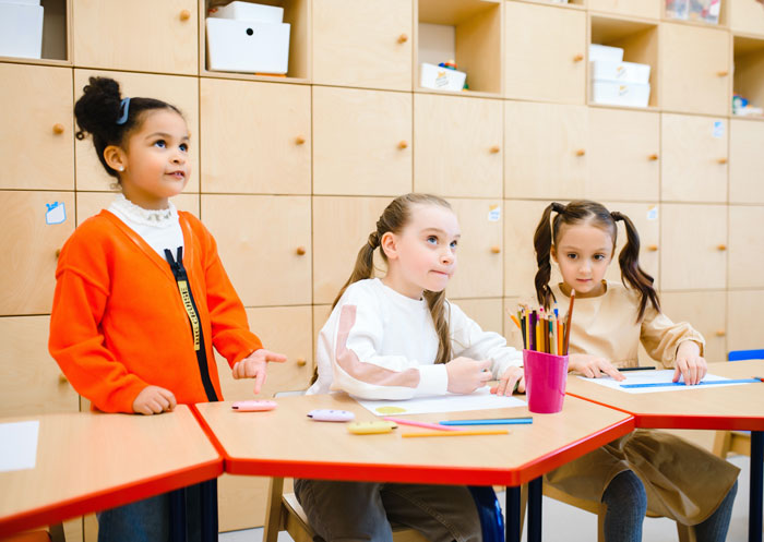Three schoolgirls in classroom engaged in drawing, featuring curious facts about art classes and creative activities.