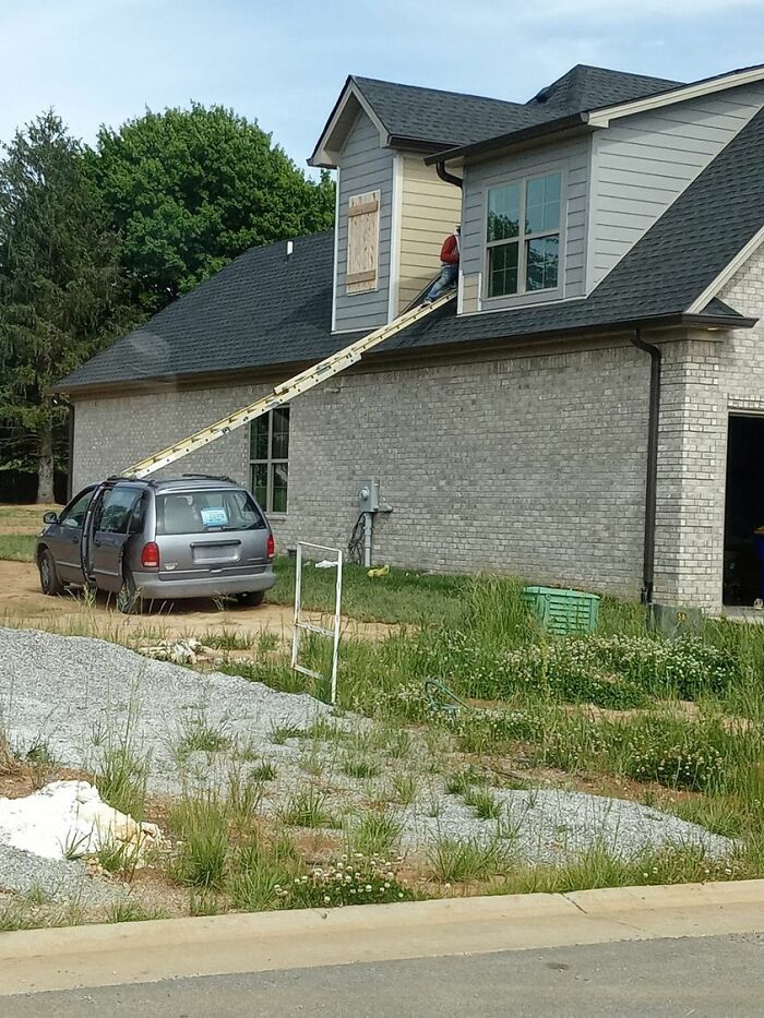 A person on a roof using a car to support a ladder, ignoring OSHA safety regulations.