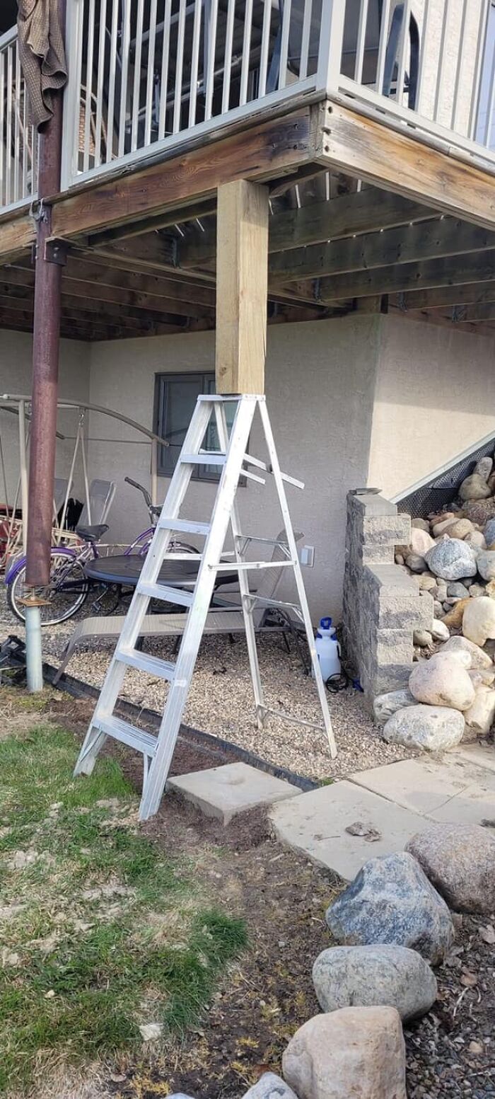 Ladder supporting a deck beam in a risky DIY setup, ignoring OSHA safety guidelines.
