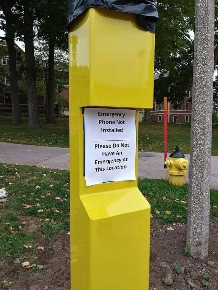 Yellow emergency phone station without phone, humorously advises against emergencies, ignoring safety regulations.
