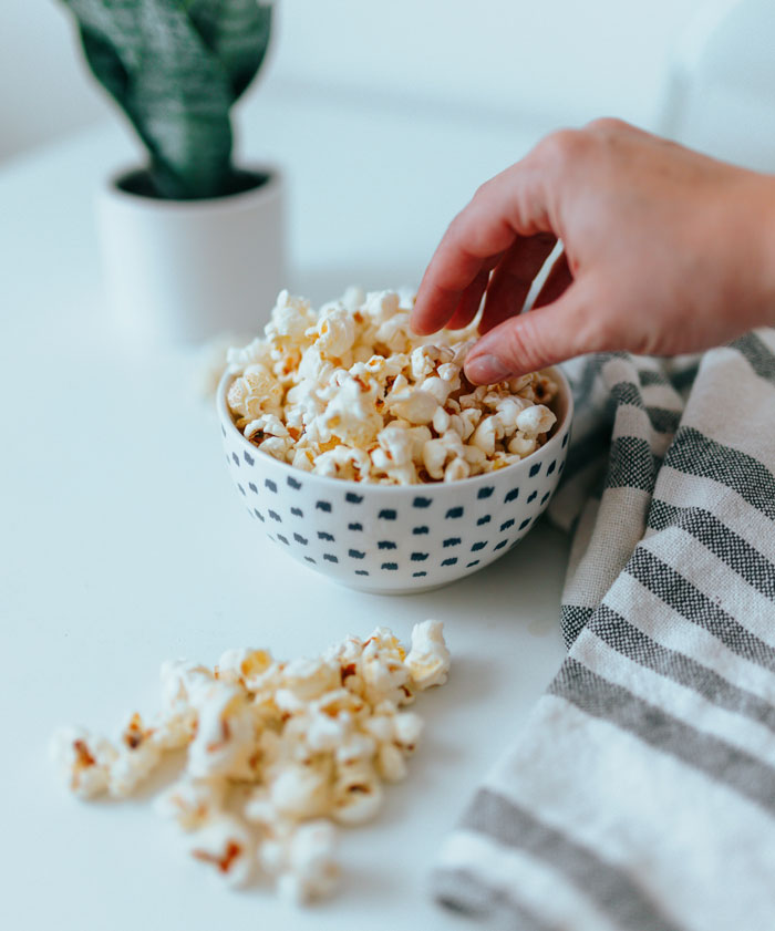 A hand reaching out to popcorn 