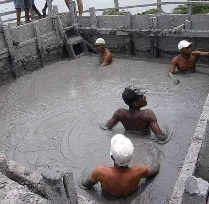 Workers standing in wet concrete, seemingly ignoring OSHA safety regulations.