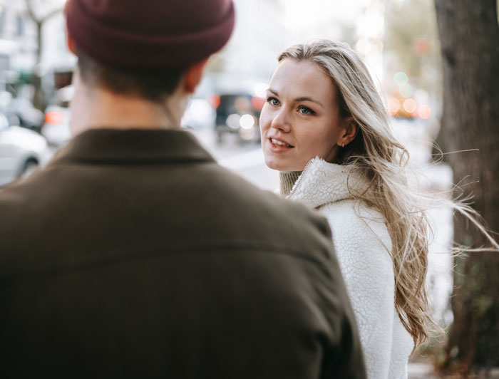 Young woman talking to man on street